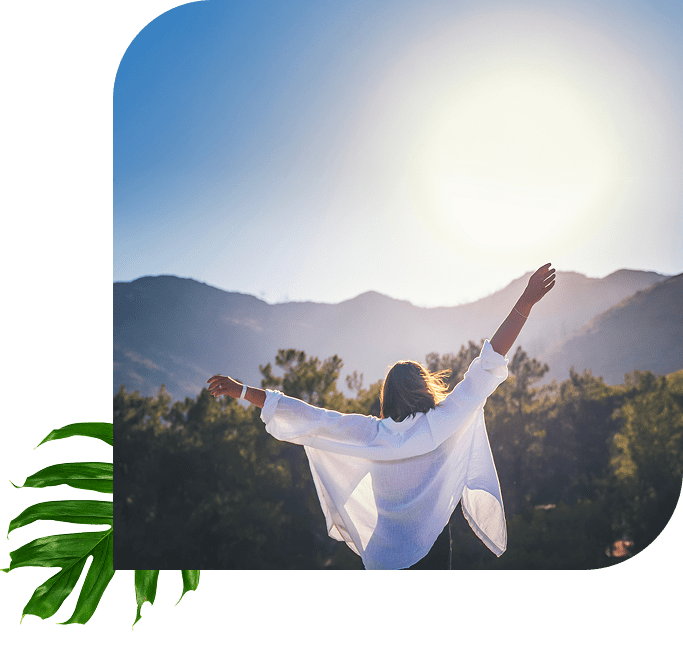 Person with arms raised enjoying sunrise in nature.
