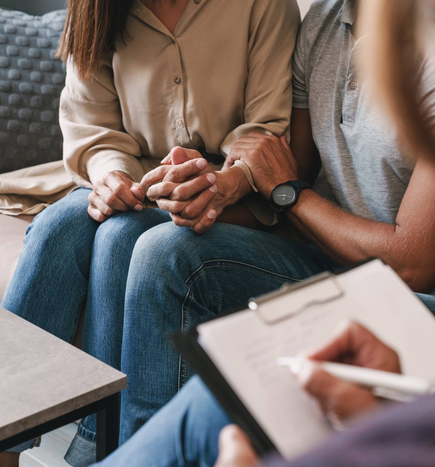 Two people holding hands during a counseling session.